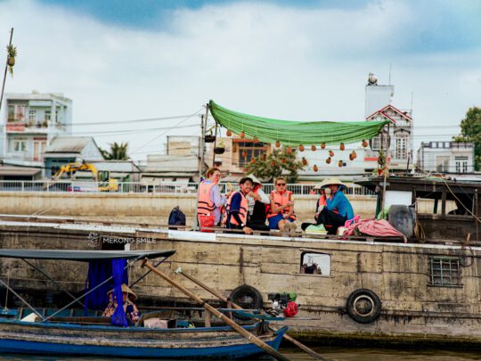 A person enjoying fresh, juicy pineapple served directly from a vendor's boat at the floating market on canh tho city tour