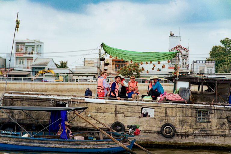 A person enjoying fresh, juicy pineapple served directly from a vendor's boat at the floating market on canh tho city tour