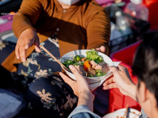 A steaming bowl of Hu Tieu, a popular Vietnamese noodle soup, enjoyed for breakfast on a boat on can tho city tour