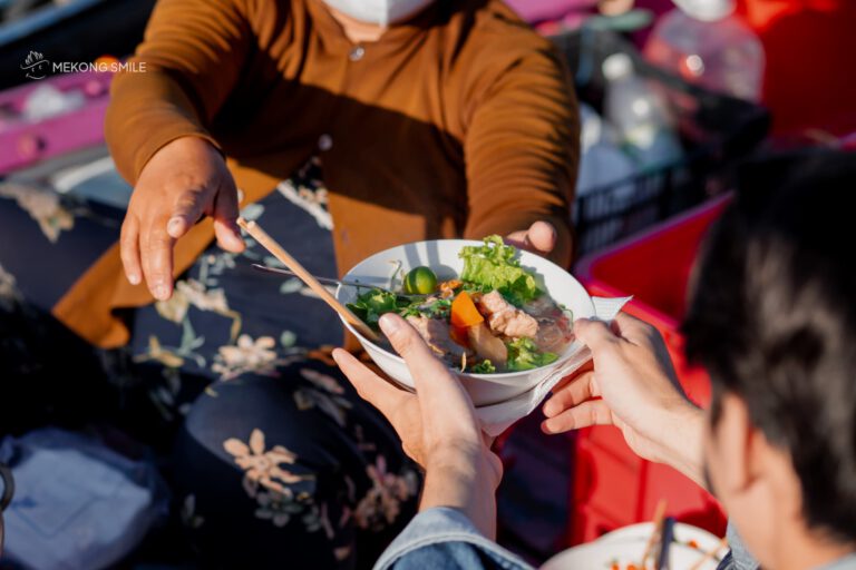 A steaming bowl of Hu Tieu, a popular Vietnamese noodle soup, enjoyed for breakfast on a boat on can tho city tour