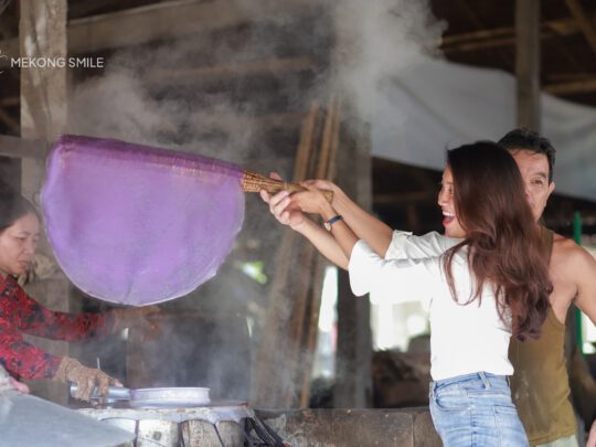 A tourist getting a hands-on experience, learning to make rice noodles at a local workshop on can tho city tour
