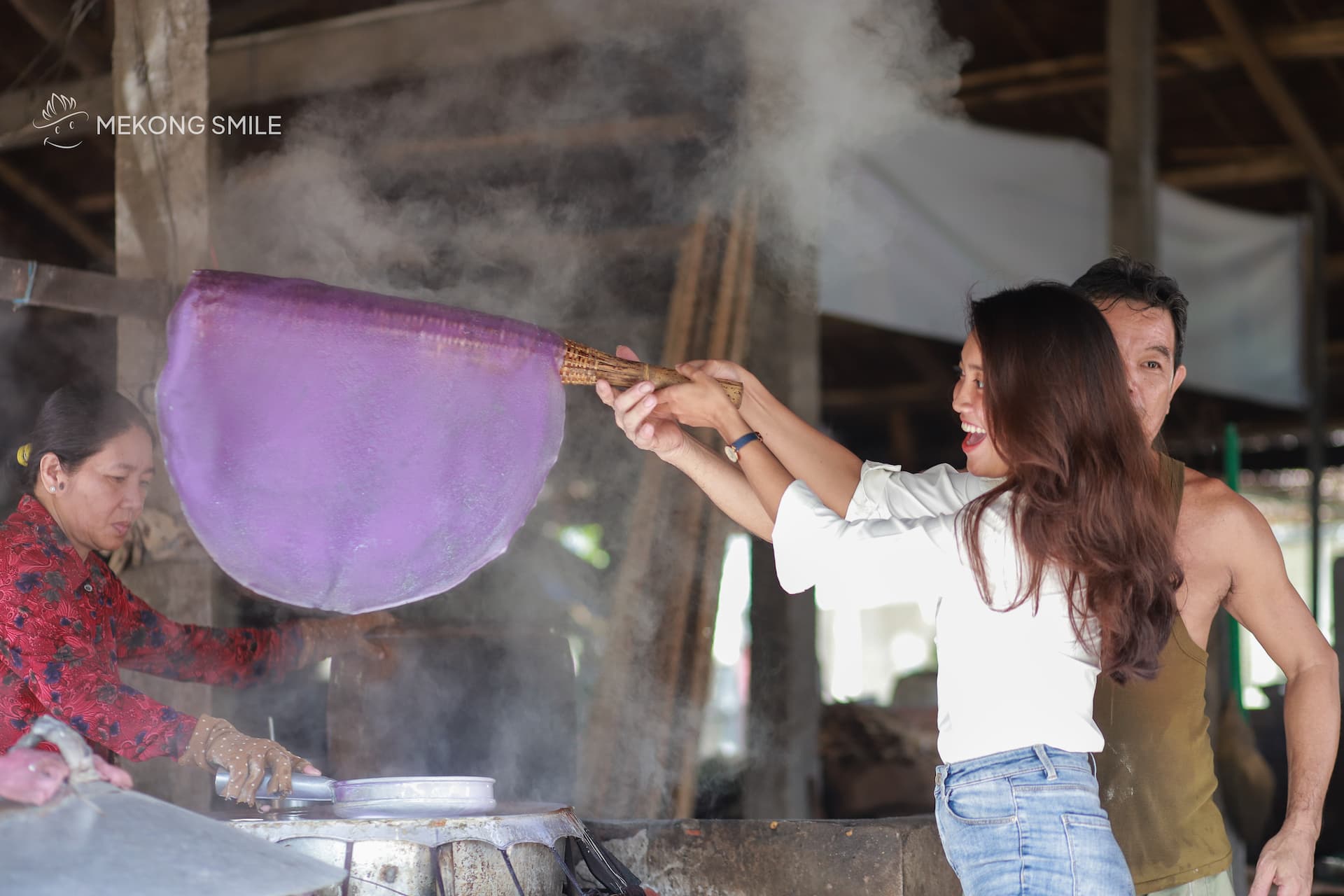 A tourist getting a hands-on experience, learning to make rice noodles at a local workshop on can tho city tour