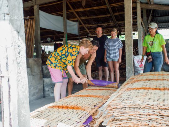A tourist carefully spreading rice paper batter onto a steamer, a hands-on experience at a workshop.