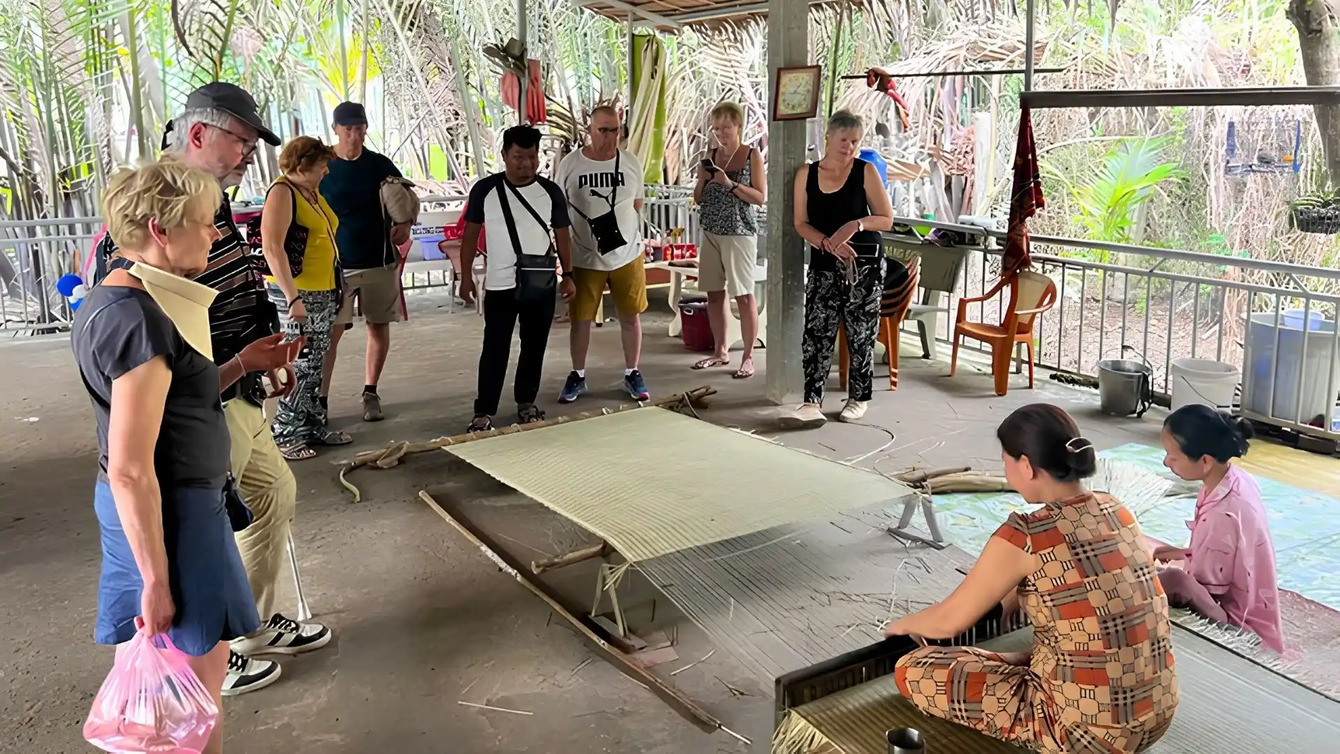 An Hiep Mat Weaving Village: A Hidden Craft Village in Ben Tre 157 A group of visitors gathered around a weaving station at An Hiep Mat Weaving Village