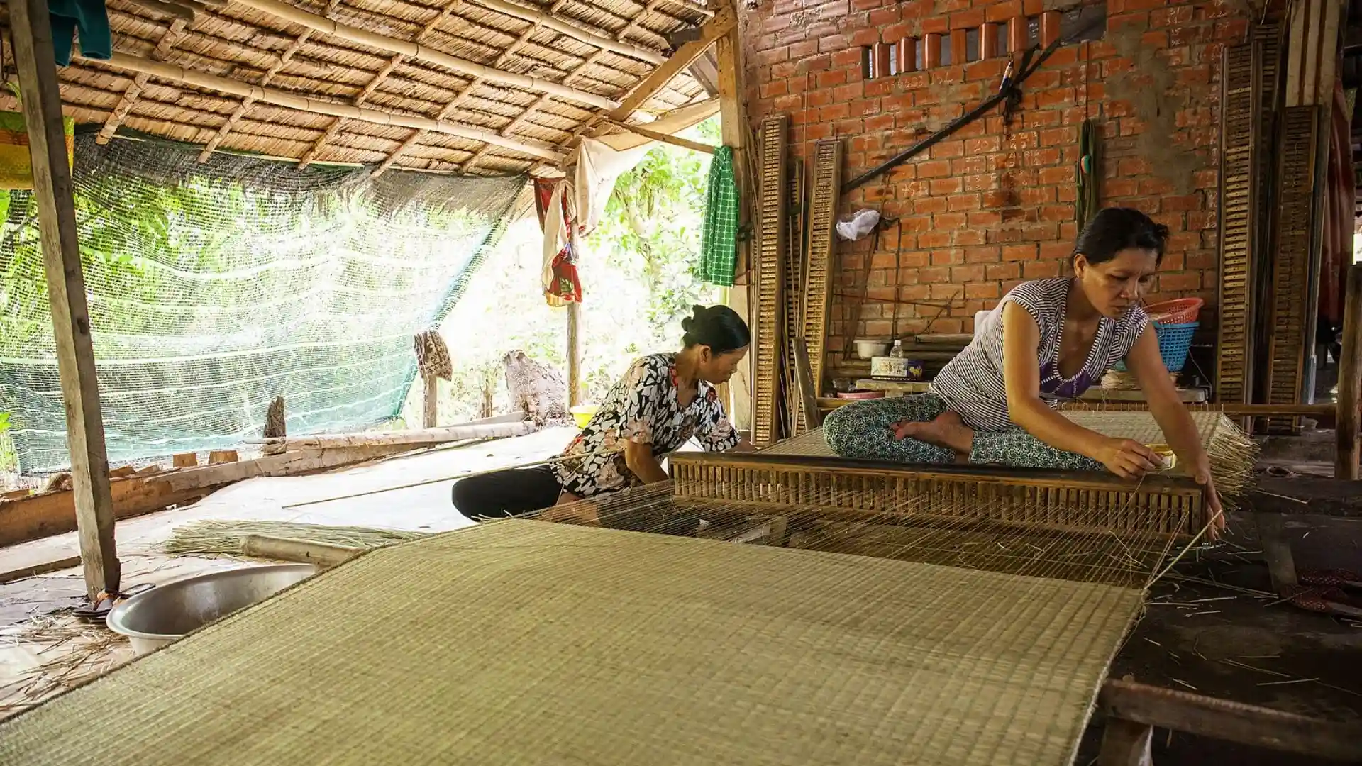 An artisan meticulously weaving a patterned mat at An Hiep Mat Weaving Village