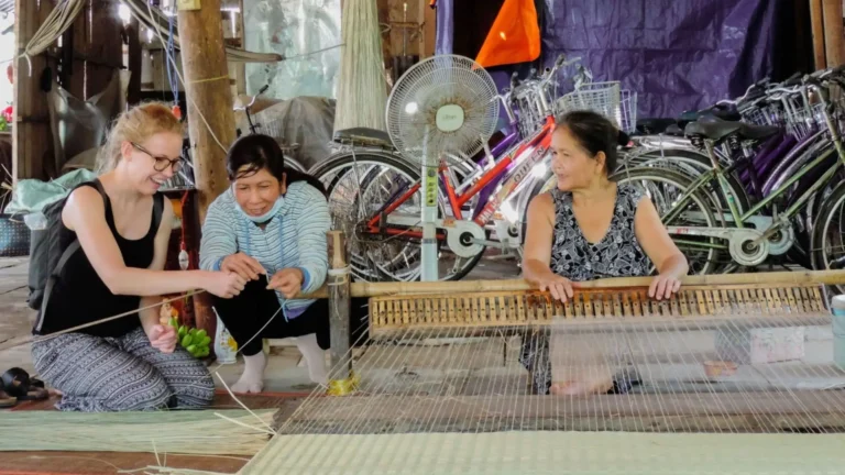 Tourists observing a local artisan at work in An Hiep Mat Weaving Village