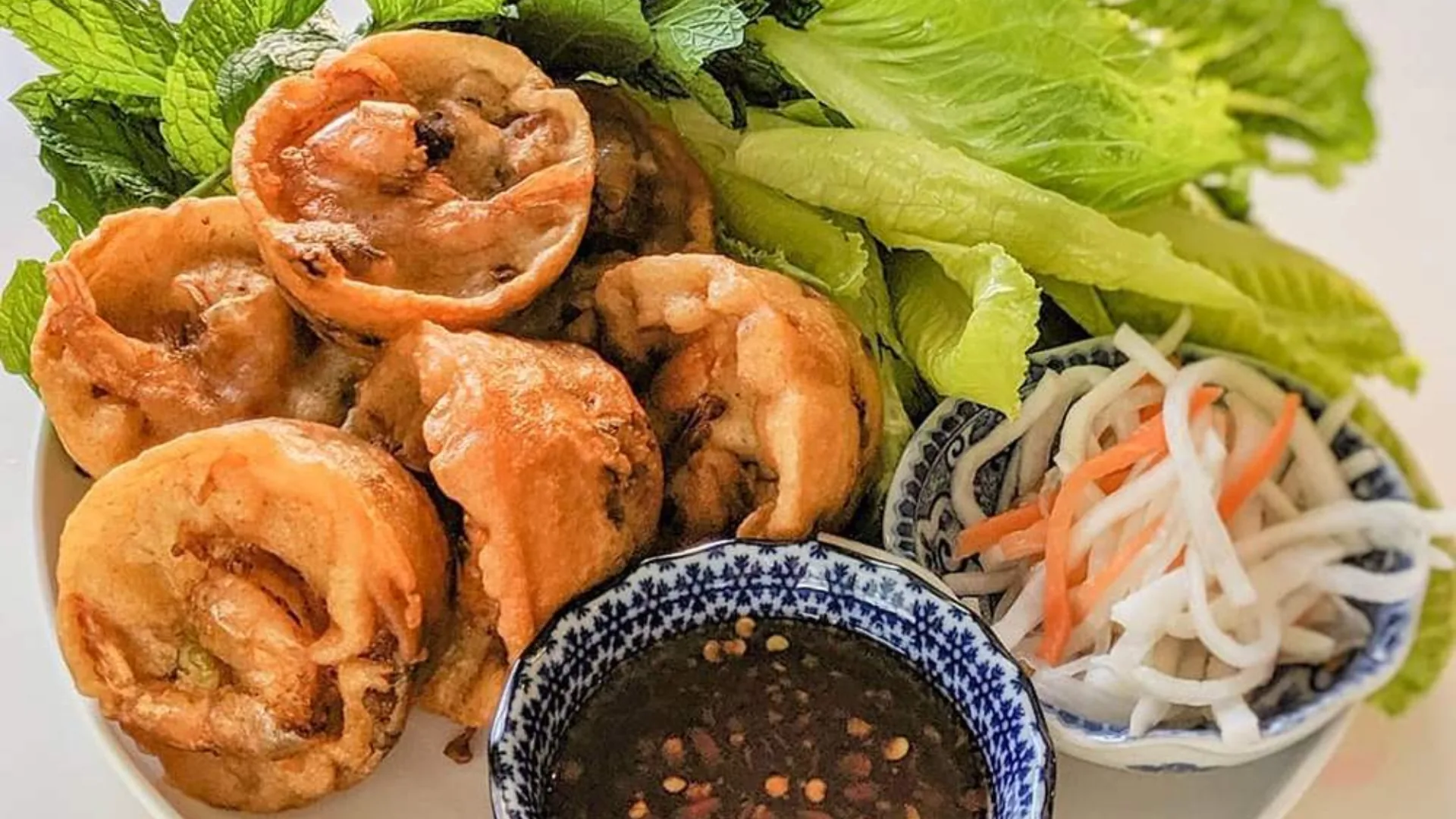 Banh Cong – crispy shrimp cakes from Can Tho, deep-fried to golden perfection and served with fresh herbs
