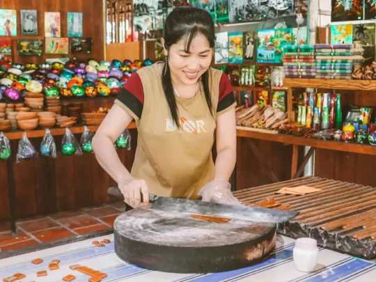 A skilled artisan expertly cutting a large sheet of cooled coconut candy into small, uniform pieces
