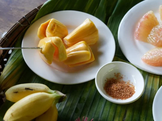 A colorful platter of fresh tropical fruits like pineapple, mango, and jackfruit served to tourists in Ben Tre