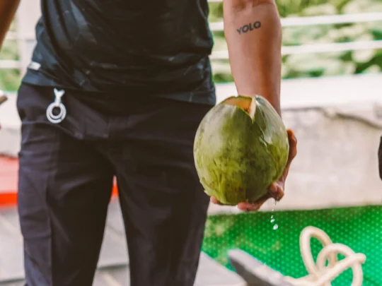 A friendly Mekong Smile tour guide carefully chopping a fresh coconut for a guest in Ben Tre