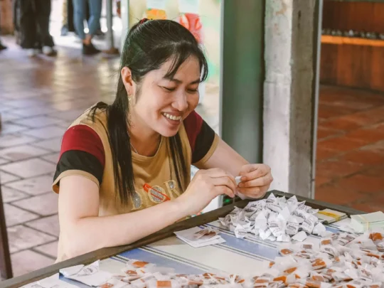 Local women quickly and skillfully hand-wrapping individual pieces of coconut candy in a workshop
