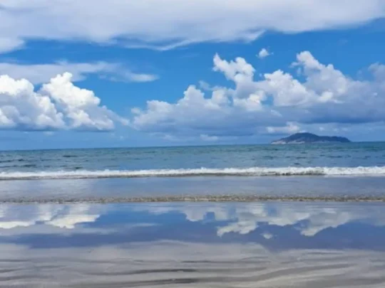 Blue sky and reflective shoreline at Vong Beach on the Bamboo Lagoon Con Dao tour