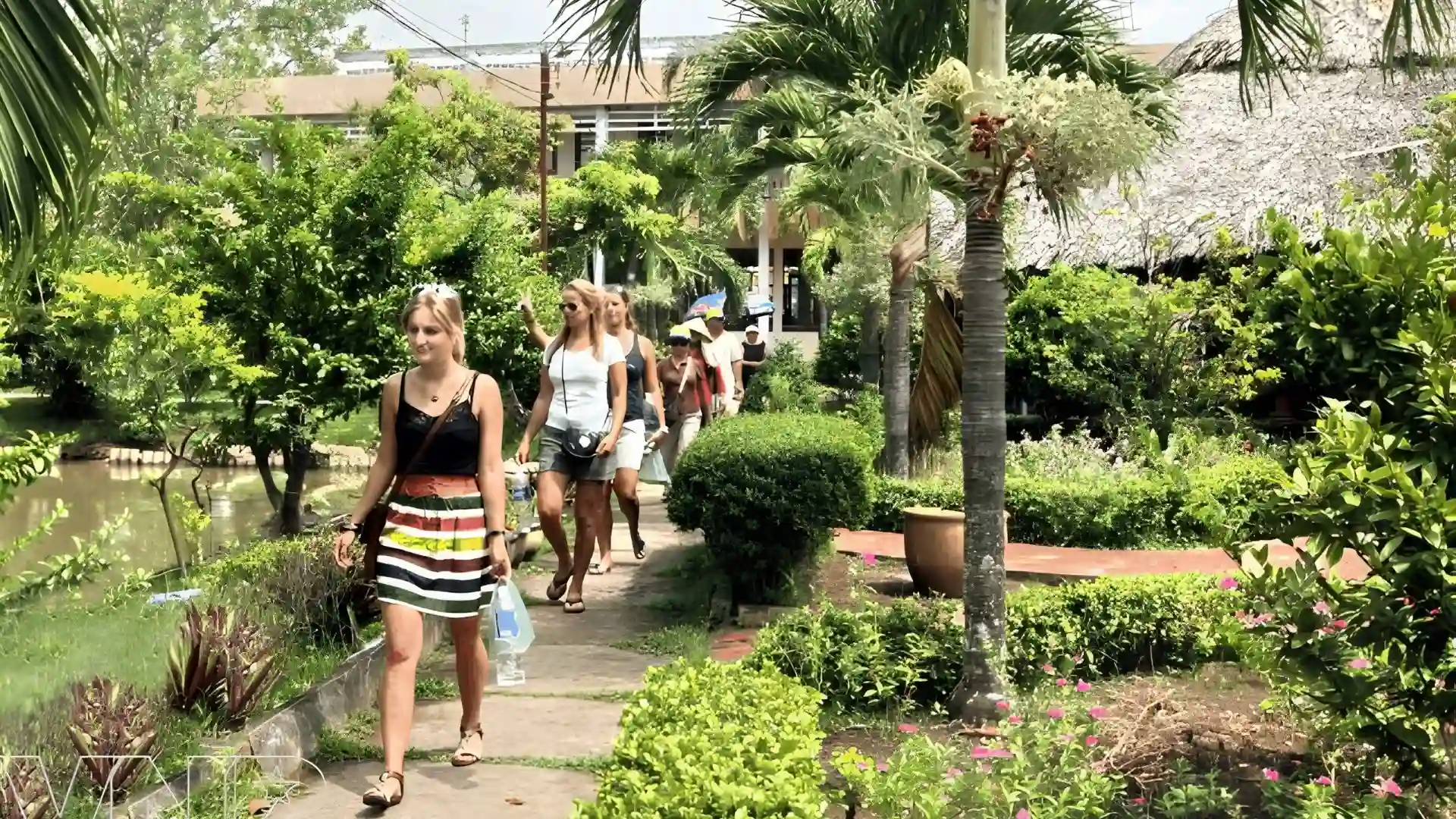 Tourists walking through a botanical garden at Cai Mon Orchard Village