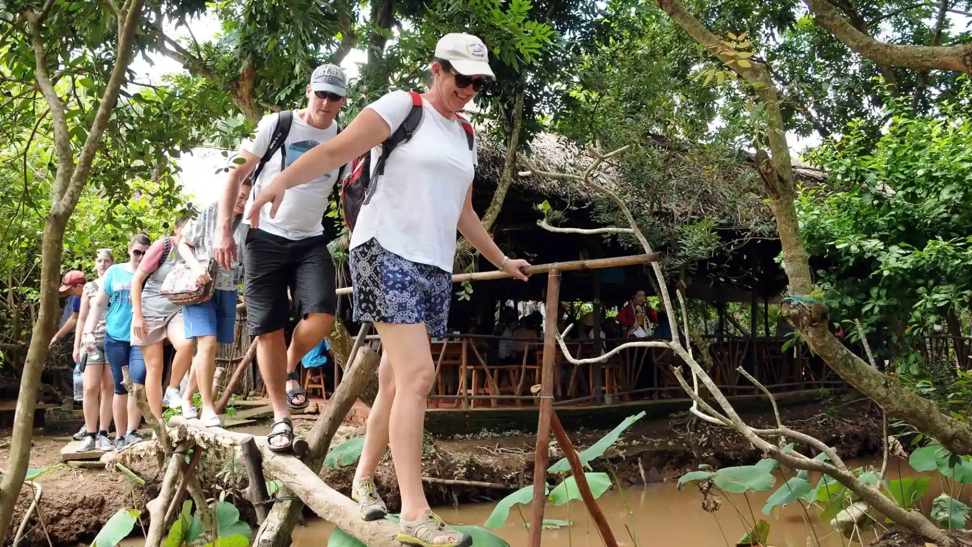 Visitor crossing a traditional monkey bridge in Cai Mon Orchard Village