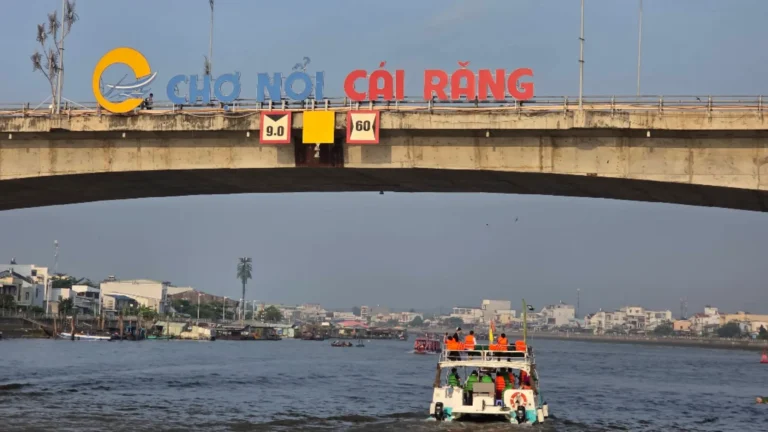 Boat passing beneath the Cai Rang Floating Market sign in Can Tho