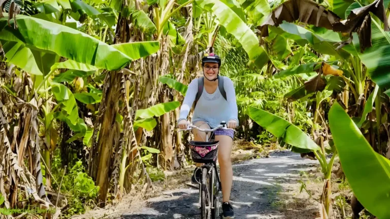 People cycling along a quiet, scenic countryside road, surrounded by lush greenery and a peaceful atmosphere.