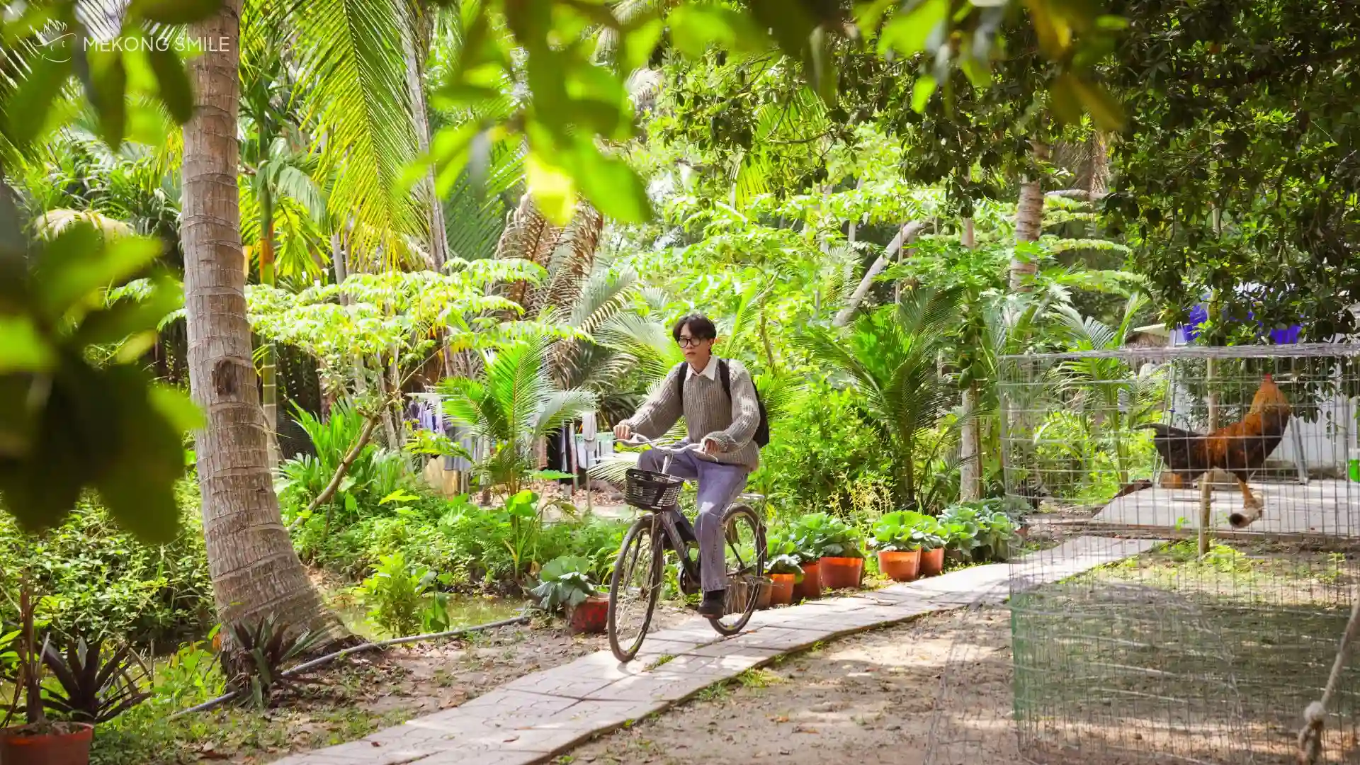 A group of cyclists passing through a traditional Vietnamese village path, experiencing authentic local life.