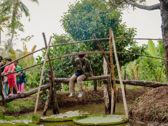A person attempting to cross a narrow "monkey bridge," a fun and wobbly challenge on the tour.