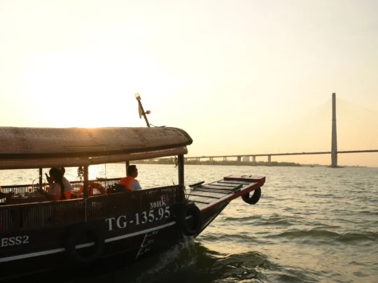 Can Tho Bridge glowing in the distance during sunset – Mekong Smile Can Tho Sunset Tour