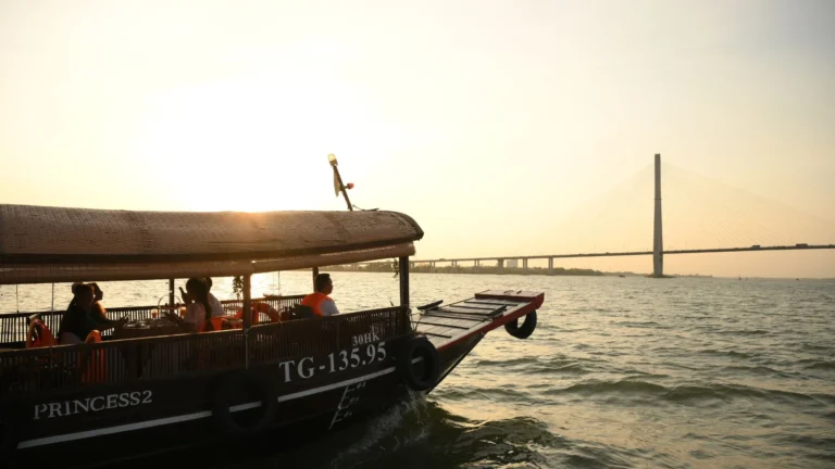 Can Tho Bridge glowing in the distance during sunset – Mekong Smile Can Tho Sunset Tour