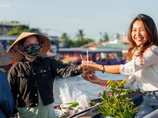 A traveler buying a cup of traditional Vietnamese morning coffee from a small boat on the Cai Rang Floating Market.