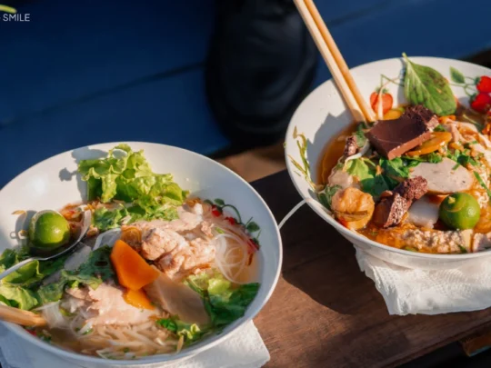 A close-up shot of a steaming bowl of Hu Tieu noodle soup, Cai Rang floating market tour