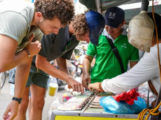 A friendly local guide providing hands-on instruction to a traveler during a Can Tho cooking class.