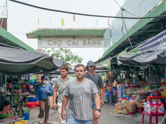 A tour group visiting a traditional Vietnamese market in Can Tho to buy fresh ingredients for their cooking class.