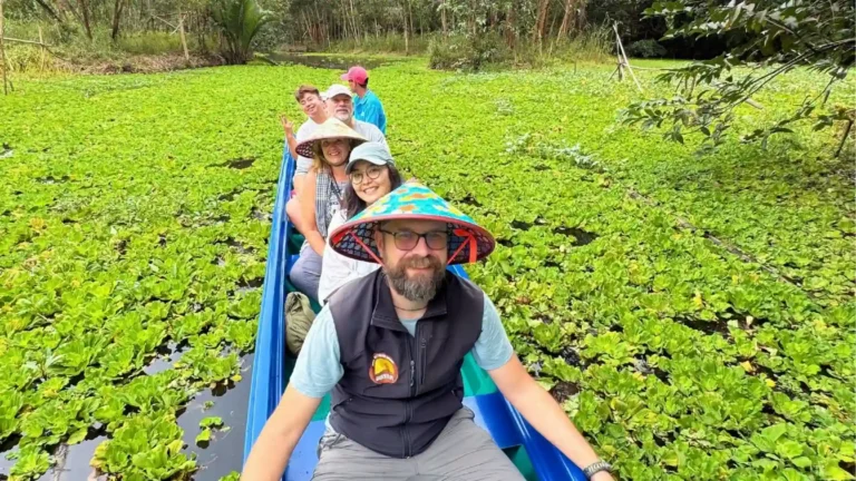International visitors taking a small boat through a green wetland landscape in Can Tho
