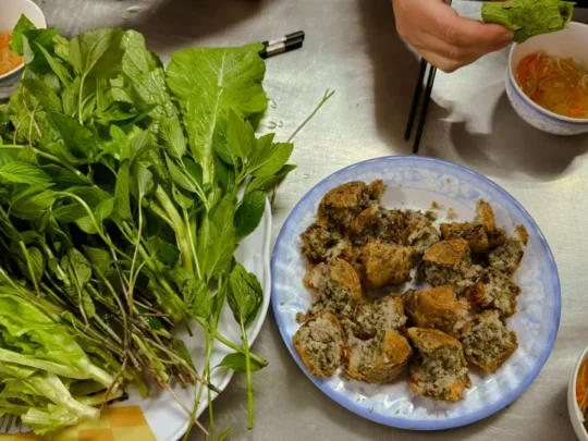 Bánh Cống served with fresh herbs, lettuce, and a traditional fish sauce for dipping
