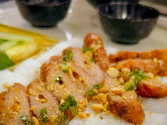 A beautifully arranged Nem Nướng dish with vibrant colors from the fresh herbs and vegetables