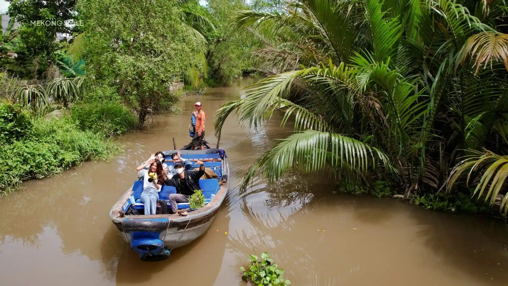 A tourist posing for a photo with the beautiful, rustic countryside scenery of the Mekong Delta as a backdrop
