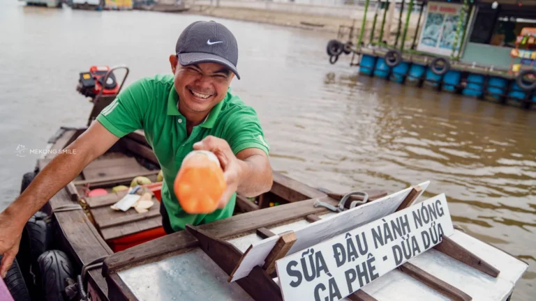 friendly local vendor smiling at tourists, showcasing the warm hospitality on our Can Tho Floating Market & Fruit Garden Tour
