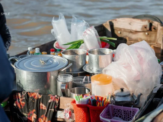 A local vendor preparing a hot bowl of Vietnamese noodle soup on a small floating kitchen boat in Can Tho