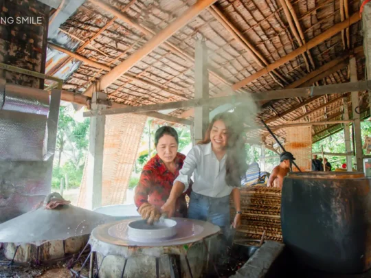 A tourist trying their hand at the rice noodle making in Can Tho River Tour