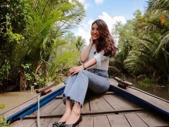 A person sitting in a boat, enjoying the serene view while cruising along a canal in the Mekong Delta.