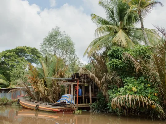 Traditional stilt houses built along the water's edge on a small canal in Can Tho, Vietnam.