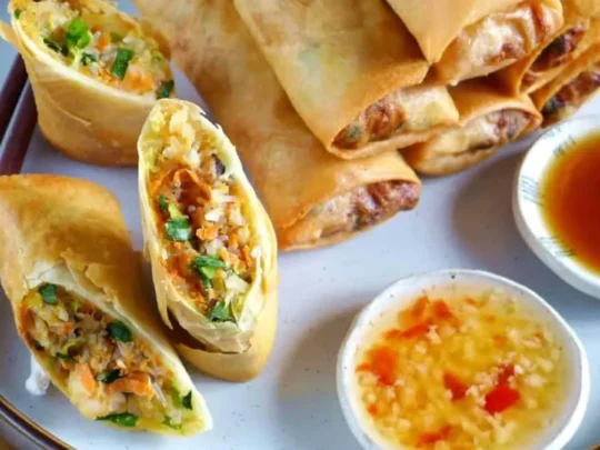 Golden-yellow Crispy Fried Spring Rolls served with a side of traditional sweet and sour dipping sauce