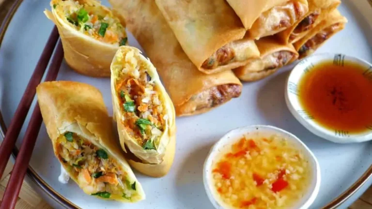 Golden-yellow Crispy Fried Spring Rolls served with a side of traditional sweet and sour dipping sauce