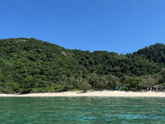 Beach view of Cau Island Con Dao with clear water and green hills