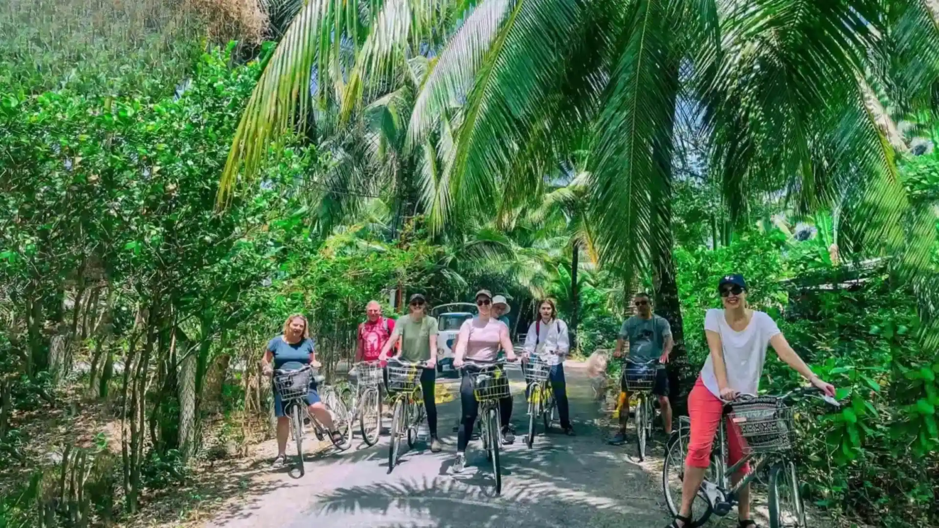 When to Visit the Mekong Delta: Weather, Seasons & What to Expect 10 Travelers cycling along a shaded rural path in the Mekong Delta