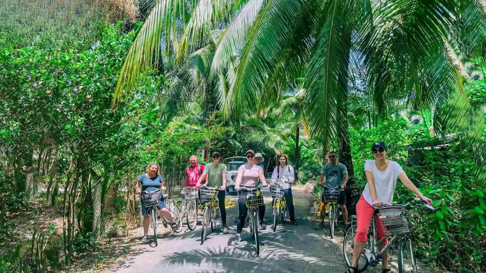 Mekong Delta Travel Guide: Where to Go and How to Plan Your Trip 10 Travelers cycling along a shaded rural road in the Mekong Delta countryside
