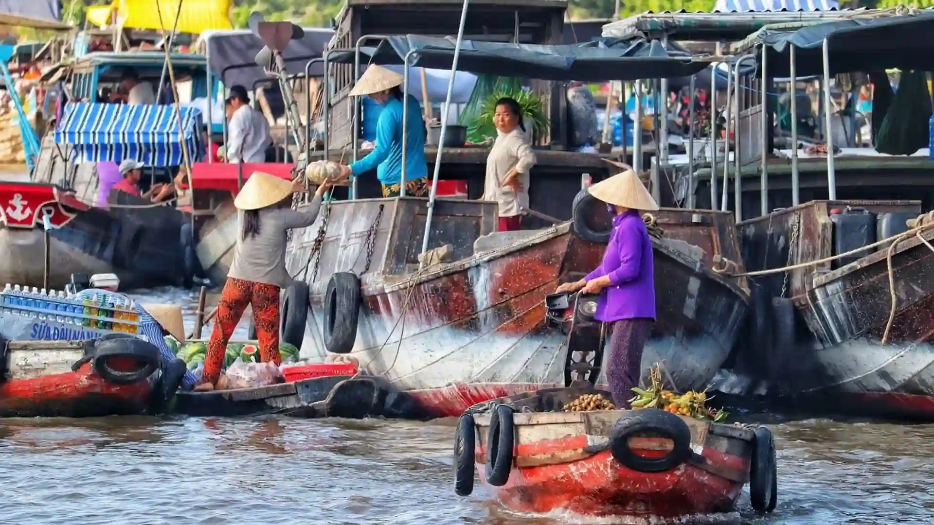 Vietnam Travel Guide for First-Time Visitors 23 Local traders handling goods on wooden boats at a floating market in the Mekong Delta