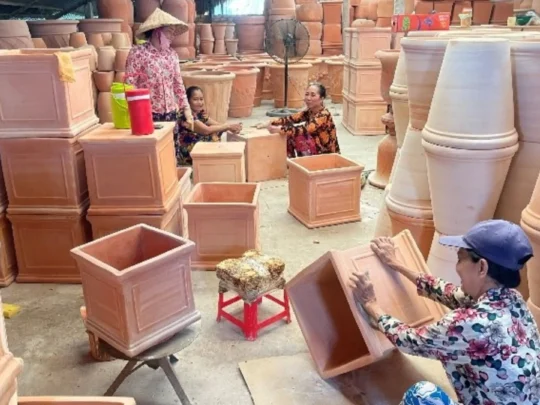 Local artisan hand-making traditional red clay pottery at the An Binh workshop