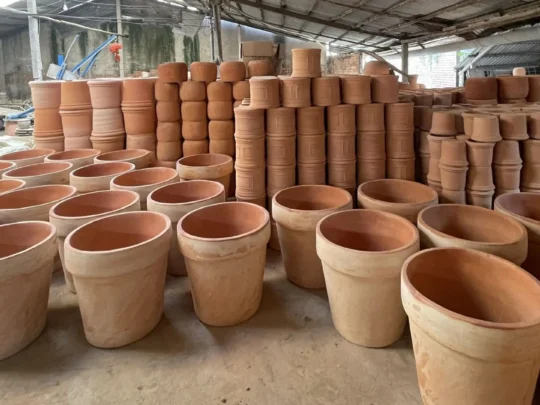 Stacks of handmade red clay pottery and bricks ready for firing in an binh islet tour