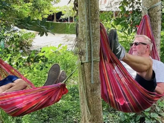 Tourist relaxing in a rope hammock under the trees in An Binh Islet tour