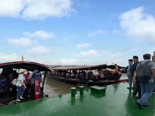 Tourists getting picked up by a traditional boat at Vinh Long pier for the An Binh Islet tour