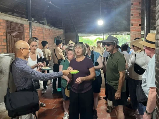 Tourists tasting pop rice at a local snack-making workshop in An Binh Islet Tour