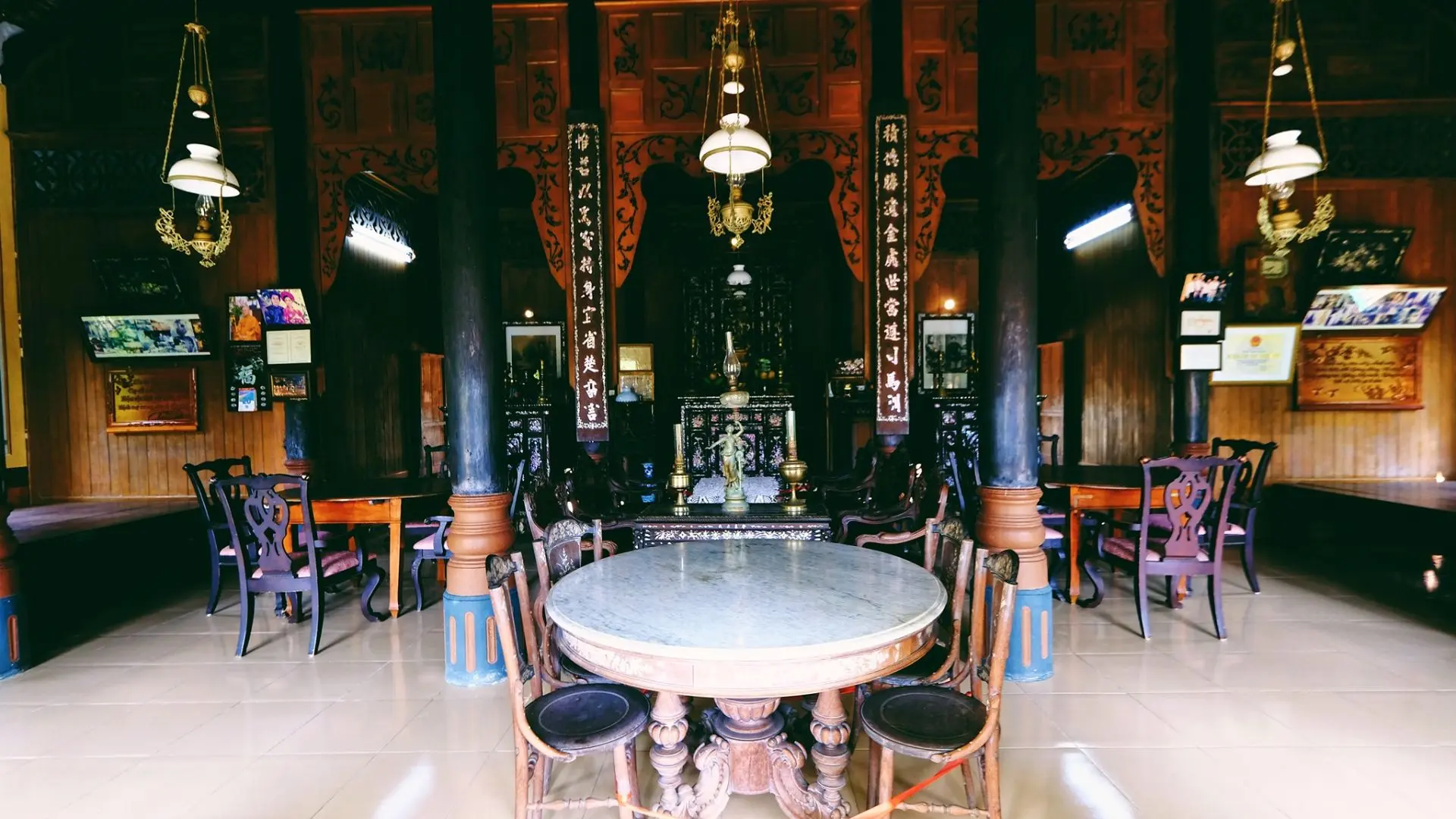 The central living room of Ba Duc Ancient House featuring antique wooden tables and traditional Vietnamese décor
