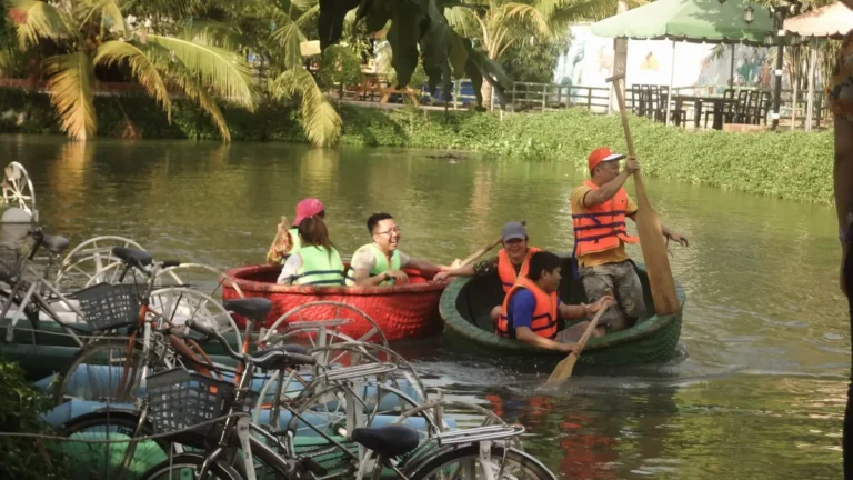 Visitors taking a boat ride through canals at Bao Gia Trang Vien Ecological Village